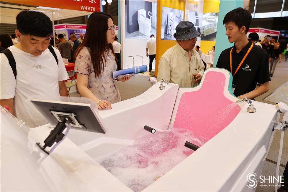 Visitors check out a set of smart bathing equipment at China Aid, an exhibition of senior-care products.jpeg